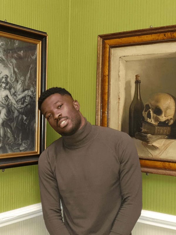 Jonge zwarte man poseert tussen twee schilderijen in een museum