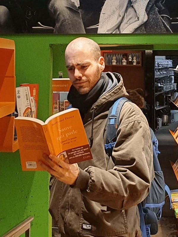 Jonge blanke man leest een open boek van een verdoofde man in een bibliotheek